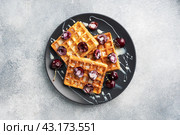 Belgian fluted waffles with fresh cherries and cream on a plate. Soft homemade waffles, sweet dessert with cherries. copy space. Стоковое фото, фотограф Глущенко Елена / Фотобанк Лори