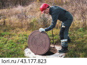 On a septic sewer well, a worker opens the manhole cover. Plumbing work. Стоковое фото, фотограф Коханова Наталья / Фотобанк Лори