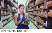 In warehouse of store, girl checks quantity of goods and receipt documents for products. Стоковое видео, видеограф Яков Филимонов / Фотобанк Лори