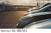 Cars in a row in the parking lot in the sunset against the background of freeway traffic. Switching from out of focus to focus. Стоковое видео, видеограф Ярославский Максим / Фотобанк Лори