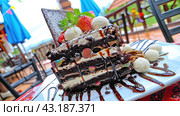 A piece of festive chocolate sponge cake on a plate in an empty cafe. Стоковое AI-изображение, AI-художник Ярославский Максим / Фотобанк Лори