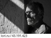 Black and white portrait of a mature, unkempt man against a wall with hard shadows. Prisoner in prison. Стоковое AI-изображение, AI-художник Коханова Наталья / Фотобанк Лори