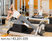 Girl in different poses performs static and dynamic exercises on reformer. Стоковое фото, фотограф Яков Филимонов / Фотобанк Лори