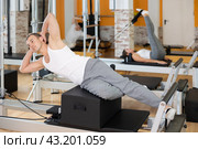 Man in different poses performs static and dynamic exercises on reformer. Стоковое фото, фотограф Яков Филимонов / Фотобанк Лори