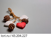 Композиция из деревянных сердечек и шишек на сером фоне. Стоковое фото, фотограф Елена Баранова / Фотобанк Лори