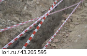 Red white barrier tape trenches. Focus on red and white barrier tape at construction site. Ribbons indicate dug trenches. Стоковое видео, видеограф svetograph / Фотобанк Лори