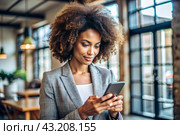 A businesslike dark-skinned African-American woman with curly hair. She is dressed in a casual jacket. In the hands of a smartphone. A businesswoman looks at her mobile phone. Стоковое AI-изображение, AI-художник Photojuli / Фотобанк Лори