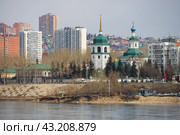 Вид на Собор иконы Божией Матери Знамение в Знаменском монастыре. Город Иркутск, Иркутская область, Россия. Красивая православная церковь. На переднем плане река Ангара. Вдали жилые дома. Стоковое фото, фотограф Андрей Степанов / Фотобанк Лори