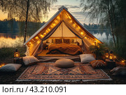 Luxury glamping camping tent with cozy accessories, light garlands and beautiful landscape at sunset. Glamping by night poster. Colorful lights and garlands. Стоковое AI-изображение, AI-художник Ирина Михайличенко / Фотобанк Лори