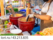 Street food in Asia. A food vendor prepares Som Tam salad at the night food market. Mixing chopped vegetables and spices in a wooden mortar. Стоковое фото, фотограф Коханова Наталья / Фотобанк Лори