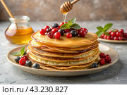 Delicious pancakes with honey, berries, blueberries, cranberries and raspberries. The concept of the Russian holiday Maslenitsa. Стоковое AI-изображение, AI-художник Photojuli / Фотобанк Лори