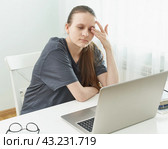 Girl rubs her eyes, her eyes are tired from strain and hurt. Concept of harmful effects of computer. Стоковое фото, фотограф Natalia Gdovskaia / Фотобанк Лори