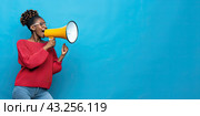 An African woman protests while filming using a loudspeaker on a blue background. Copy space. Стоковое AI-изображение, AI-художник Ярославский Максим / Фотобанк Лори