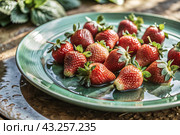 Close-up of fresh strawberries. Delicious berries and fruits are bright red with drops of water. Vegetarianism. Healthy eating. Fresh fruits on the table. Стоковое AI-изображение, AI-художник Photojuli / Фотобанк Лори