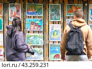 Девушка и юноша смотрят детские рисунки диких животных в заповеднике "Кивач" (2023 год). Редакционное фото, фотограф Светлана Качанова / Фотобанк Лори