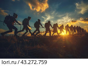 A group of people climbing a mountain against the backdrop of sunset. The climbers are silhouetted against the bright, colorful sky, creating a dramatic and inspiring effect. People are tied with rope, symbolizing teamwork and cooperation. Each of them carries a backpack and climbing equipment. The clouds and setting sun add beauty and emotion to the scene. Стоковое AI-изображение, AI-художник Анна Кривицкая / Фотобанк Лори