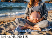 Relaxation, peace of mind, sea air. Close-up of the tummy. A pregnant woman on the beach by the sea. The concept of pregnancy, childbirth and parental responsibilities. Стоковое AI-изображение, AI-художник Photojuli / Фотобанк Лори