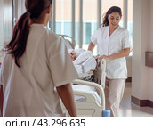 Two nurses move a bed on wheels with a bedridden patient inside the ward. Стоковое AI-изображение, AI-художник Ярославский Максим / Фотобанк Лори