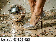 Women's legs in luxurious shiny pumps with heels at a party or disco on the background of a silver mirrored disco ball. The queen of the dance floor. Стоковое AI-изображение, AI-художник Photojuli / Фотобанк Лори