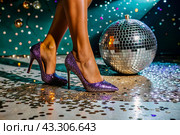 Women's legs in luxurious shiny pumps with heels at a party or disco on the background of a silver mirrored disco ball. The queen of the dance floor. Стоковое AI-изображение, AI-художник Photojuli / Фотобанк Лори