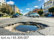 The terrible condition of the roads. A hole in the asphalt on a city street. Road repairs. A city street of poor quality. Стоковое AI-изображение, AI-художник Photojuli / Фотобанк Лори