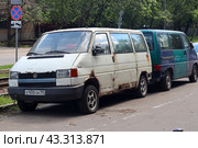 White old van parked next to a blue car. The van is parked in a parking lot. Typical urban parking area (2024 год). Редакционное фото, фотограф Константин Григорьев / Фотобанк Лори