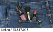 Из заднего кармана джинсов торчит косметика. Красота и мода. Вид сверху. Cosmetics sticks out of the back pocket of jeans. Beauty and fashion. Top view. Стоковое видео, видеограф Александр Собко / Фотобанк Лори