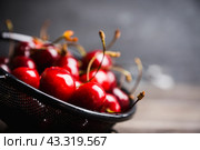 Спелая сочная черешня в дуршлаге на старом деревянном столе. Фрукты и ягоды. Малая глубина резкости. Стоковое фото, фотограф Андрей Пустякин / Фотобанк Лори