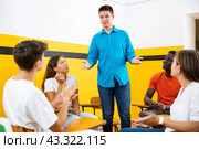 Male student discussing with groupmates sitting in circle in auditorium during classes. Стоковое фото, фотограф Яков Филимонов / Фотобанк Лори