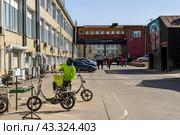 Курьер, доставляющий продукты. На сумке надпись «Кухня на районе». На стенах граффити с вагоном метро и автомобилем. Москва, Россия. (2023 год). Редакционное фото, фотограф Андрей Степанов / Фотобанк Лори