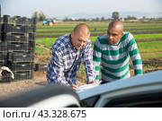 Farmer and worker signing papers near car on farm. Стоковое фото, фотограф Яков Филимонов / Фотобанк Лори