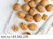 Top view walnut in endocarp, bowl with drupe in shell on white wooden cutting board. Стоковое фото, фотограф Natalia Gdovskaia / Фотобанк Лори