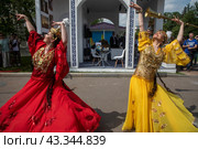 Женщины танцуют у национального стенда Узбекистана, который представлен на Российском туристическом форуме "Путешествуй!" на территории выставочного комплекса ВДНХ в городе Москве, Россия (2024 год). Редакционное фото, фотограф Николай Винокуров / Фотобанк Лори