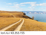 Baikal Lake. Dirt road on sandy soil in steppe with yellow meadows on Olkhon Island. Gravel road along the shore of the Small Sea on a sunny autumn day. Auto travel and outdoor recreation. Стоковое фото, фотограф Виктория Катьянова / Фотобанк Лори