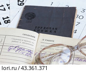 Подсчет трудового стажа. Раскрытая трудовая книжка на фоне листков календаря и очки. Выход на пенсию. Стоковое фото, фотограф Татьяна Т / Фотобанк Лори