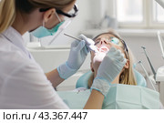 The dentist performs a preventive dental examination of the patient sitting in an armchair. Close-up. Стоковое AI-изображение, AI-художник Ярославский Максим / Фотобанк Лори
