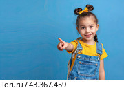 The little girl smiles and points in front of her with her hand. Copy space. Стоковое AI-изображение, AI-художник Ярославский Максим / Фотобанк Лори