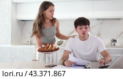 Concentrated guy sitting at computer and a girl persuading to give him pasty in the kitchen. Стоковое видео, видеограф Яков Филимонов / Фотобанк Лори