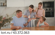 Dissatisfied woman screaming and demanding money from perplexed husband counting received salary at table in kitchen, two teenage girls standing nearby. Стоковое видео, видеограф Яков Филимонов / Фотобанк Лори
