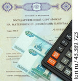 Государственный сертификат материнский (семейный) капитал, калькулятор и российский деньги (2024 год). Редакционное фото, фотограф Цибаев Алексей / Фотобанк Лори