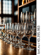 Empty glasses stands in row on rack bar for restaurant backgrounds, full frame. Close-up of wine or champagne clean glasses in row prepared by bartender for event ceremony. Copy ad text space design. Стоковое AI-изображение, AI-художник Aleksandr Golubev / Фотобанк Лори