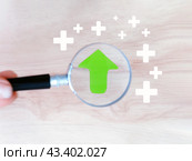 Концепция роста и приумножения. Увеличенная лупой зеленая стрелка направлена вверх. Стоковое фото, фотограф Татьяна Т / Фотобанк Лори