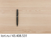 Black ballpoint pen lies on a wooden texture. Стоковое фото, фотограф Александр Собко / Фотобанк Лори