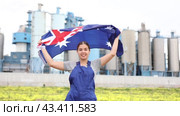 Happy young woman worker holding big flag of Australia against background of factory. Стоковое видео, видеограф Яков Филимонов / Фотобанк Лори