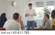 Young male coach lecturing at university with multinational students at auditorium. Стоковое видео, видеограф Яков Филимонов / Фотобанк Лори