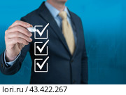Businessman hand checking the checklist boxes on blue background. Businessman with pen mark the check boxes. Hand choosing one of three options. blue background. copy space. Стоковое фото, фотограф Павел Муравьев / Фотобанк Лори