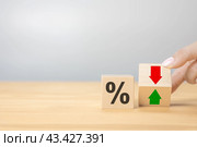 Interest rate financial and mortgage rates concept. Hand flip wood cube change arrow down to up. Wooden blocks with percentage sign and down arrow. copy space, gray background. Стоковое фото, фотограф Павел Муравьев / Фотобанк Лори