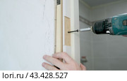 Worker attaches a door frame to the wall with a self-tapping screw. Repair and decoration of apartments. Carpentry work. Door installation. Стоковое видео, видеограф Дмитрий Кобзев / Фотобанк Лори