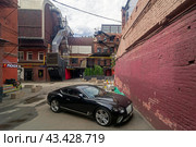 Роскошный автомобиль Бентли припаркован во дворе бывшей кондитерской фабрики "Красный Октябрь". Москва. (2024 год). Редакционное фото, фотограф Сергей Рыбин / Фотобанк Лори