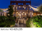 Picturesque evening view of the green garden and the EL Boutique Hotel building with night illumination. Sur city. Republic of Lebanon (2023 год). Редакционное фото, фотограф Евгений Ткачёв / Фотобанк Лори